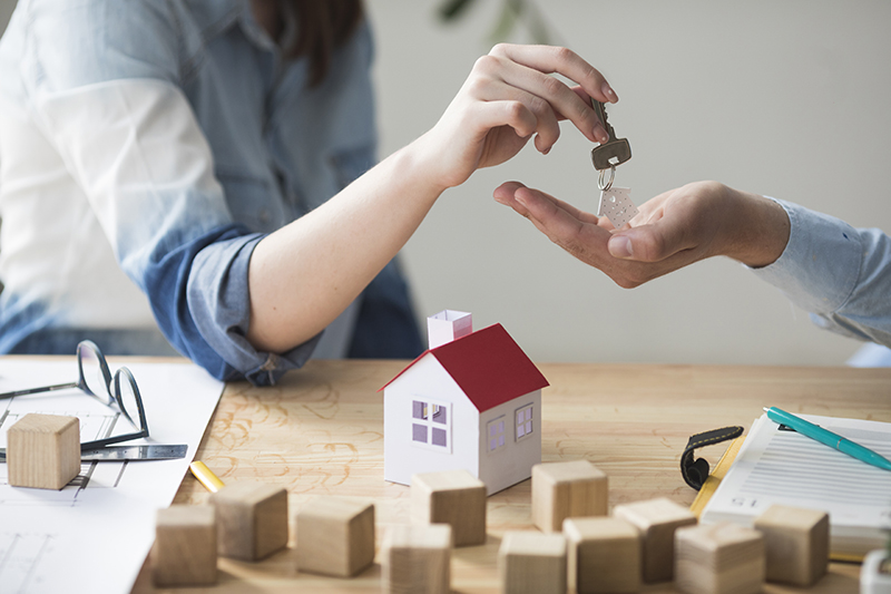 close-up-woman-s-hand-giving-house-key-man-wooden-table (2)